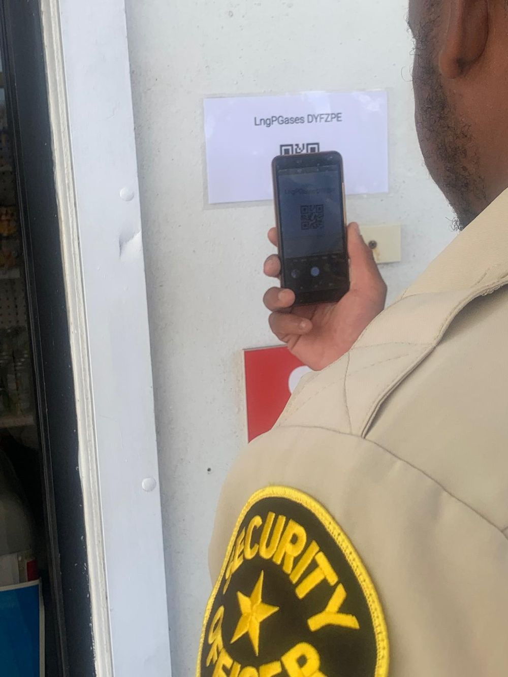 Security officer scanning the printed PunchClock QR code at a gate with his phone