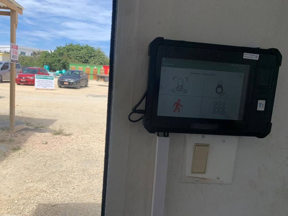 PunchClock clock on a site office wall with shipping containers and the yard behind