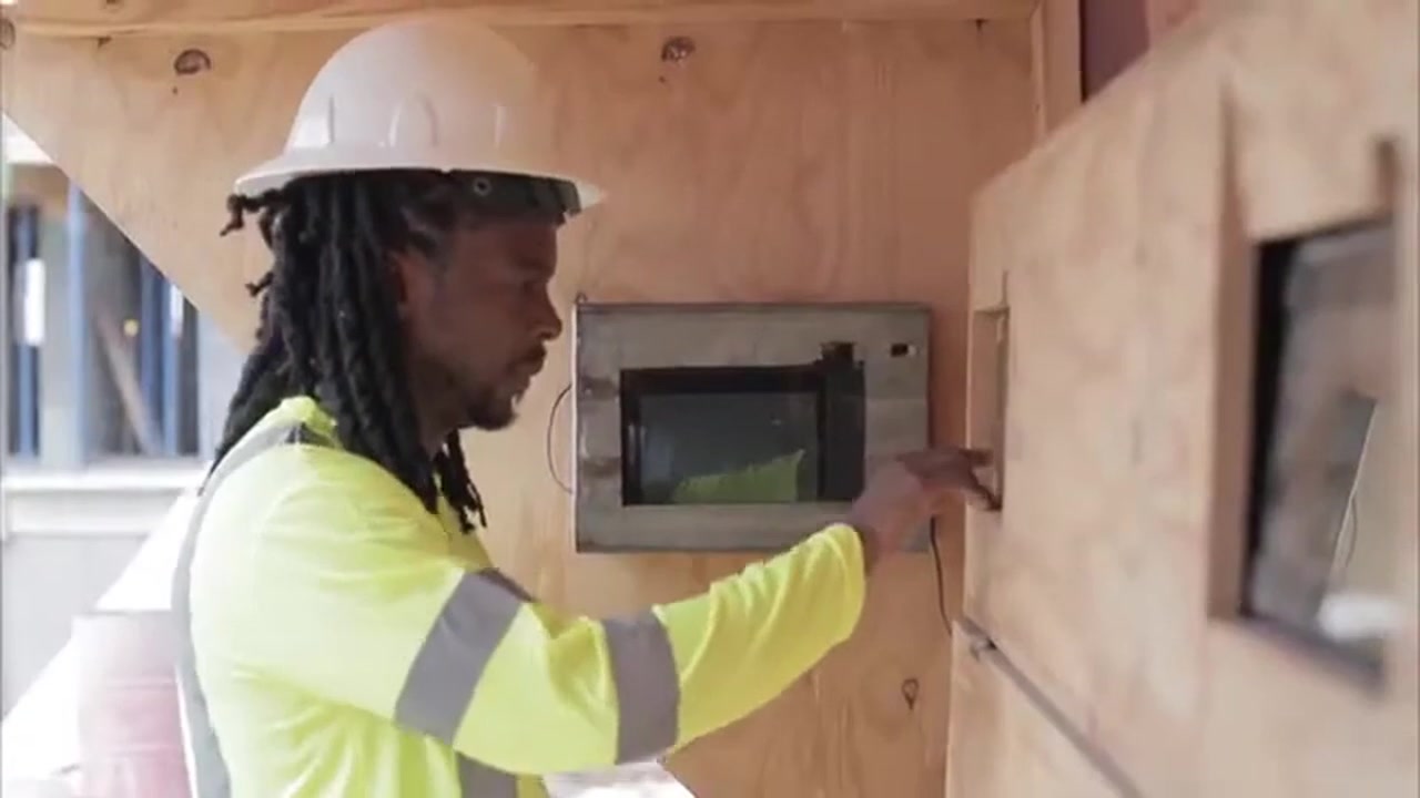 A construction worker in hi-vis clocking in at a PunchClock wall unit